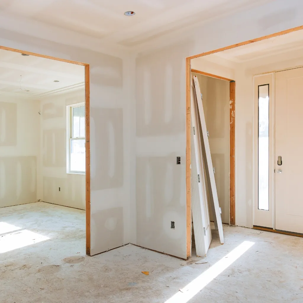 Ein Neubau mit weißer Fassade steht in einer sonnigen Siedlung